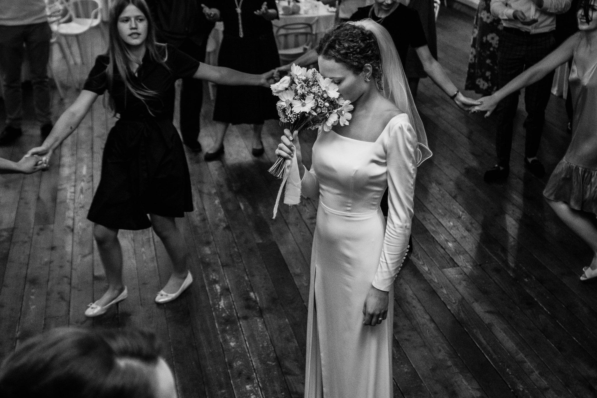 Panna młoda, otoczona kobietami, trzyma bukiet kwiatów przy twarzy