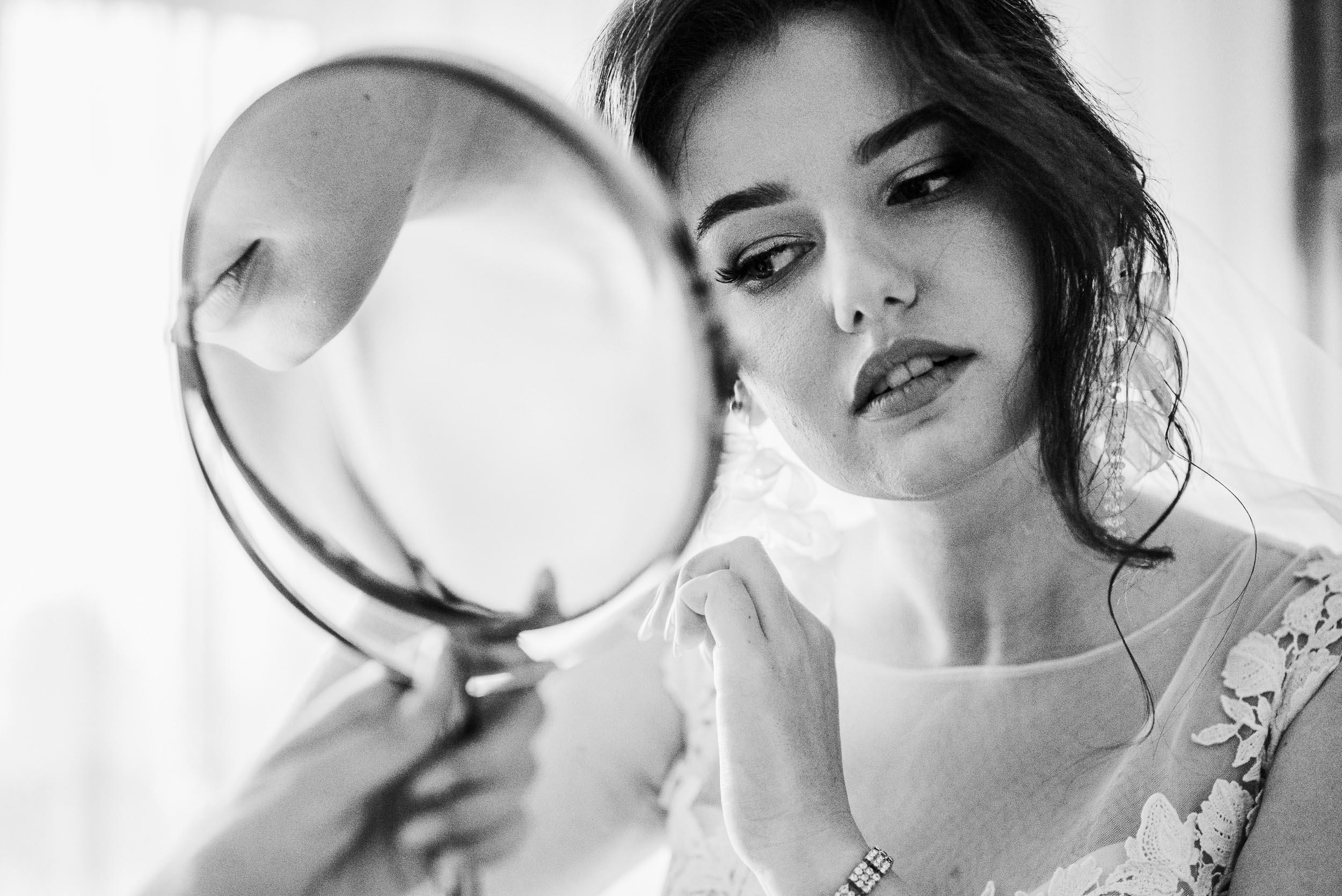 Panna młoda zakłada kolczyk patrząc się w lusterko