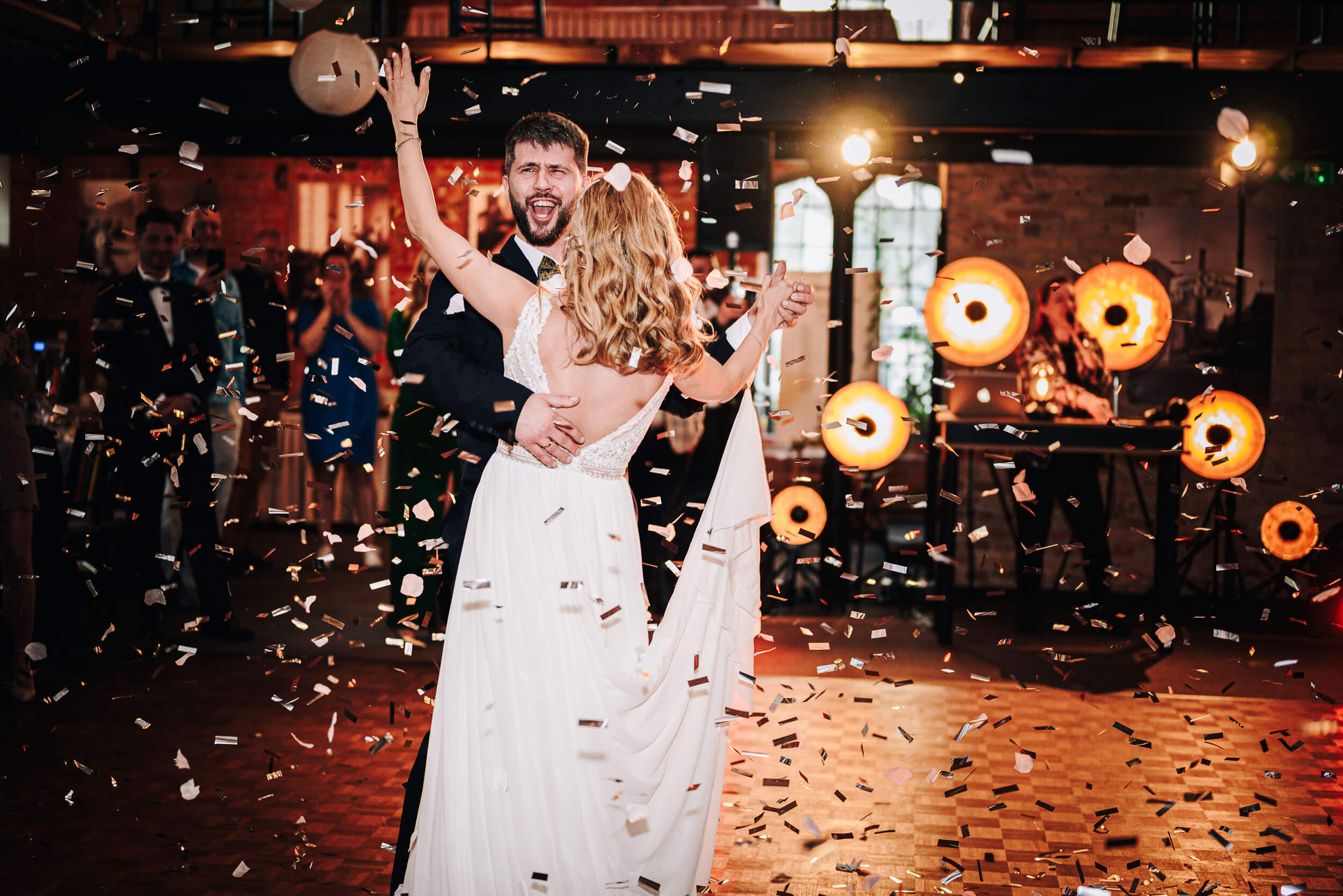 Szczęśliwa młoda para tańczy wśród spadającego konfetti