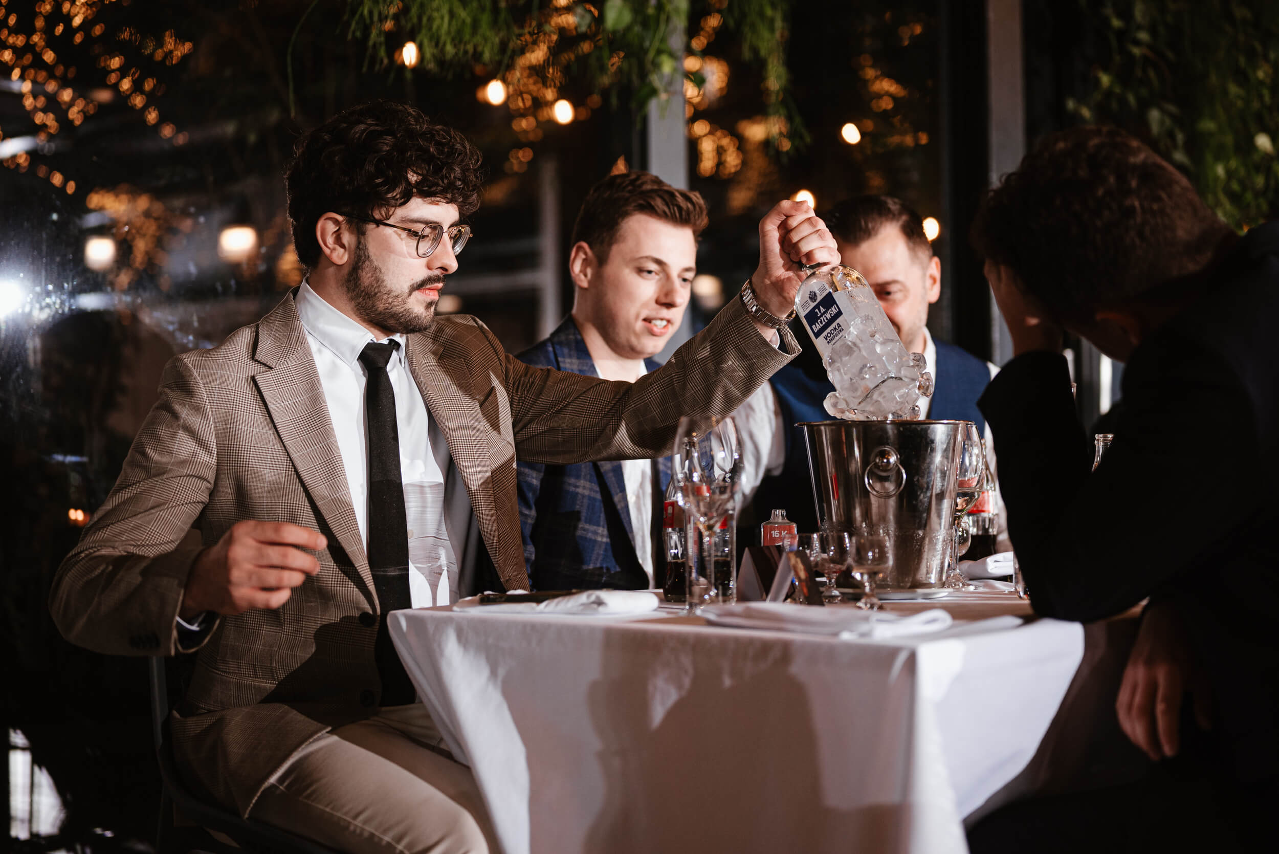 Mężczyzna wyciąga zamarzniętą butelkę wódki z wiaderka.