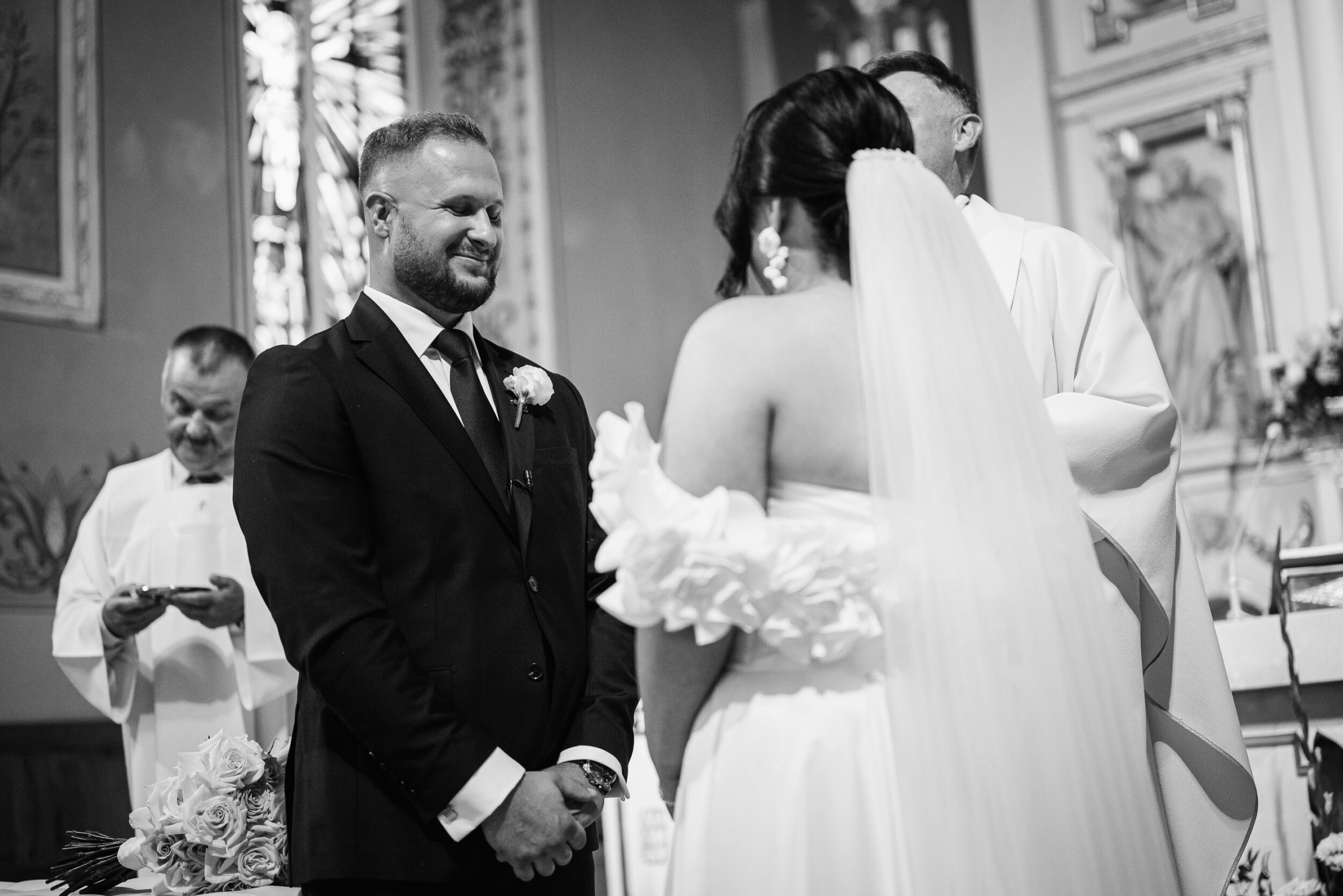 Młoda para podczas przysięgi. Pan młody ma zamknięte oczy, na jego twarzy widać wzruszenie