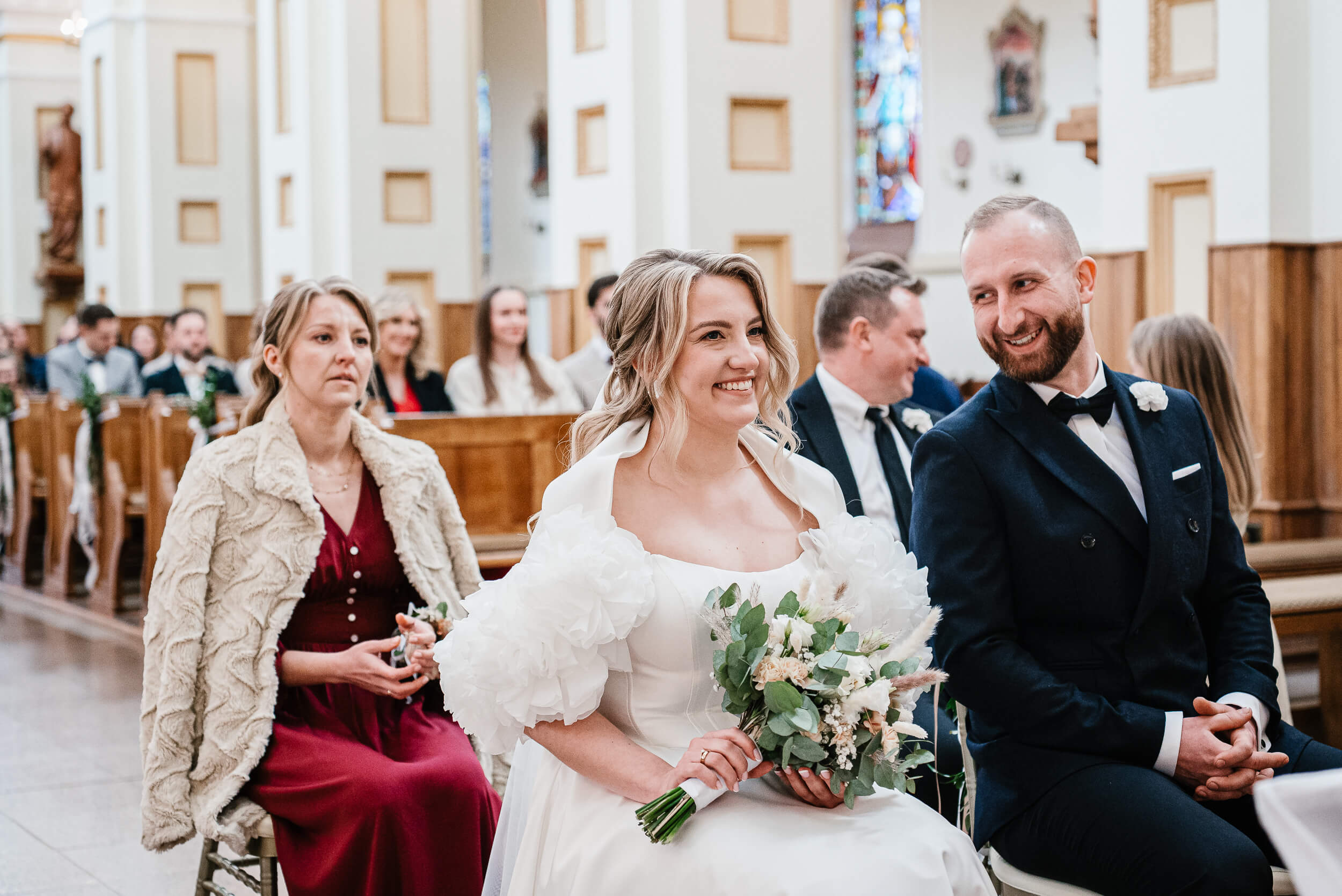 Uśmiechnięta młoda para siedzi w kościele podczas ślubu
