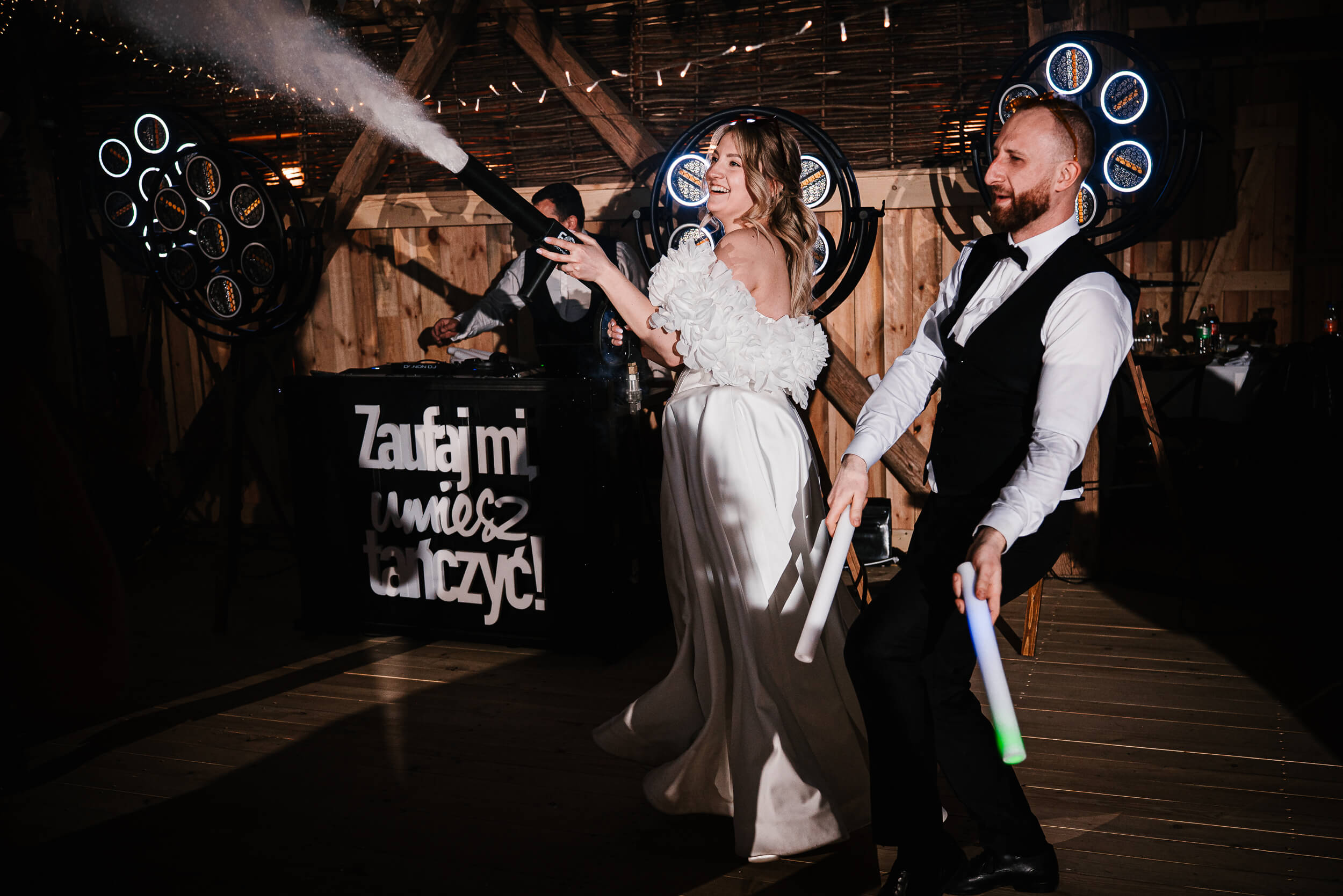 Ula i Łukasz-471 Uśmiechnięta panna młoda strzela podczas wesela z pistoletu dymem.